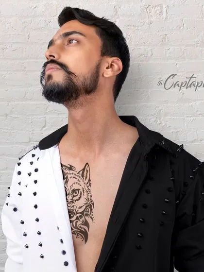An unbuttoned, stylized shot designed to showcase a model's physique and tattoos alongside the fashion. This type of edgy studio portrait adds a layer of personality and confidence to a professional portfolio.