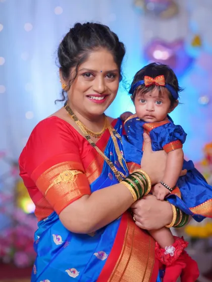 A lovely portrait of a mother holding her baby at the naming ceremony. Both are dressed in beautiful traditional attire, marking a significant family milestone.