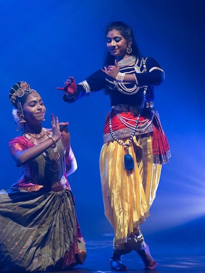 A playful interaction between Krishna and a gopi. The dancers' expressive faces and body language tell a story of divine love and friendship.