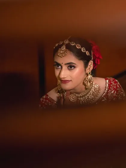 Using creative framing to capture a candid moment. This shot of the bride, taken through a gap, adds a sense of intimacy and artistic flair to her portrait.