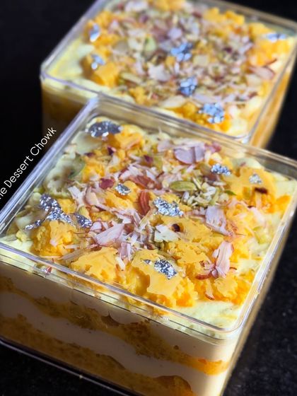 A pair of Rasmalai Cake Tubs, ready to be delivered. You can see the layers of cake and cream, topped with rasmalai chunks, nuts, and edible silver leaf.