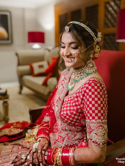A happy, smiling portrait of the bride, her face framed by her red and green jewelry. A perfect capture of her wedding day glow.
