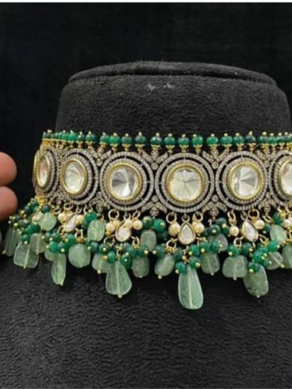 A stunning green and white kundan choker set with a modern design. The large circular kundan stones are surrounded by fine American diamond work and finished with green bead tassels, perfect for a sangeet or reception party.