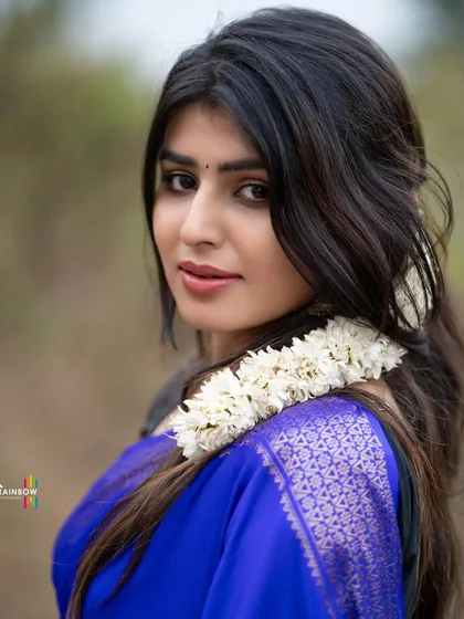 A close-up portrait of a model in a blue saree, with her hair styled with flowers, creating a classic and beautiful look.