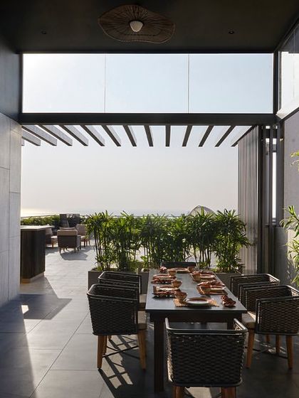 The terrace dining area is set against a backdrop of the city skyline, with a large wooden table and comfortable seating perfect for outdoor entertaining.