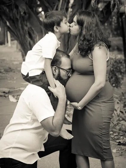 A black and white photo full of love. The dad-to-be kisses the bump, while the big-brother-to-be gives his mom a kiss. A truly precious family moment.