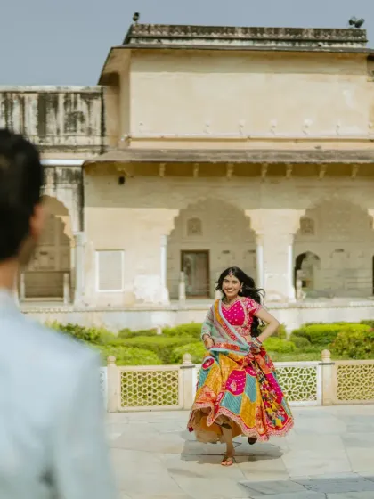 This over-the-shoulder shot creates a personal, story-driven perspective. It feels as if we are seeing the bride through her partner's eyes, running joyfully in the palace courtyard.