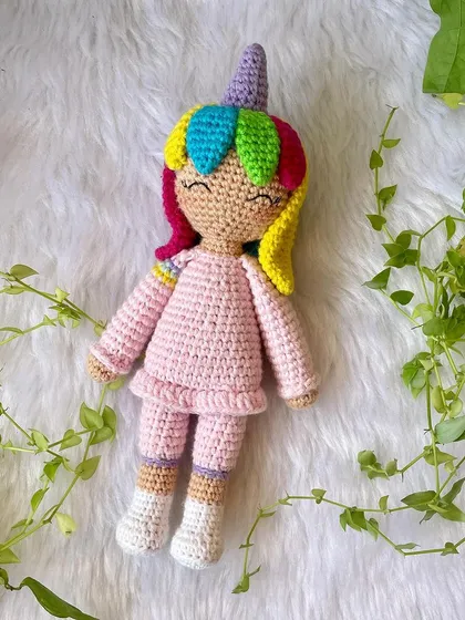 A magical unicorn doll with rainbow hair and a sparkly horn. She is dressed in a cozy pink outfit and is ready for enchanting adventures.