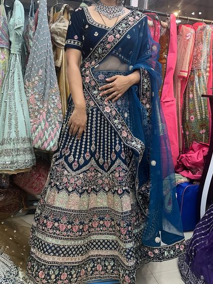 The navy blue velvet lehenga seen from another angle in my store, surrounded by other colorful options.