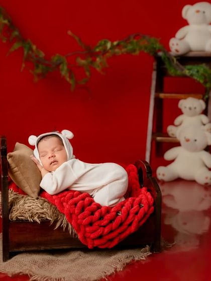 A wider view of the red-themed setup, showing the simple yet impactful arrangement with teddy bears and greenery against a bold red background.