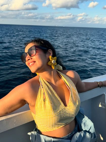 Soaking up the sun on the deck of the boat. The yellow gingham top and flower earrings are perfect for a sunny day at sea.