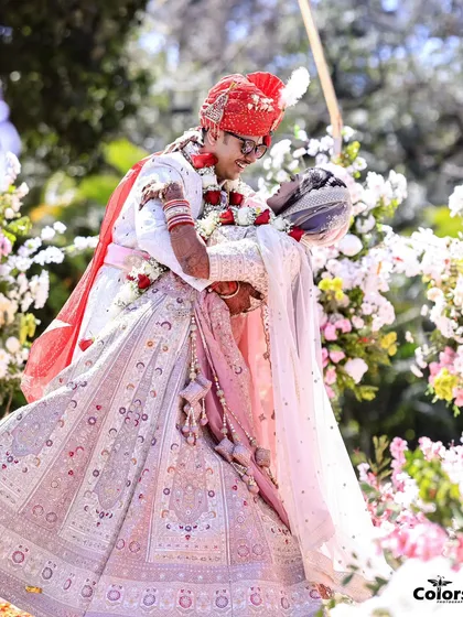 The groom joyfully lifts his bride in his arms after the Varmala ceremony, a perfect expression of happiness.