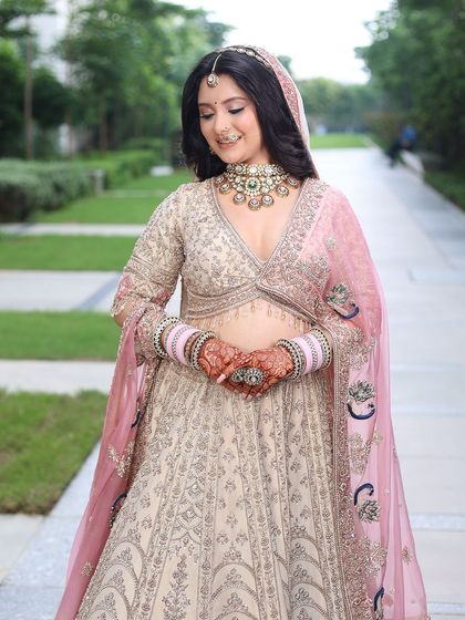 A candid moment of the bride in her pastel lehenga. The soft, natural light highlights the delicate embroidery and her radiant smile.