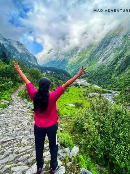 A trekker celebrating the stunning view of the Valley of Flowers. This journey is perfect for nature lovers and photographers.