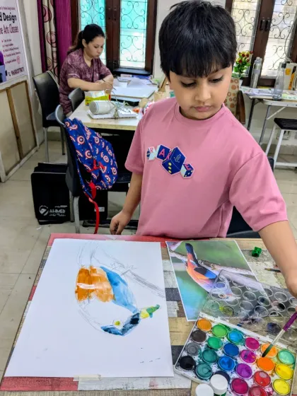 A young artist at work during our bird study class. He is carefully painting a colorful bird, using a reference photo to get the details just right.