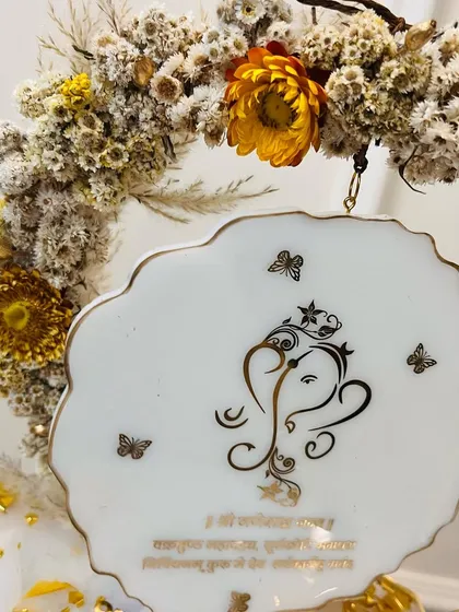 A detailed view of the hanging Ganesha plaque, surrounded by a delicate dried flower hoop.
