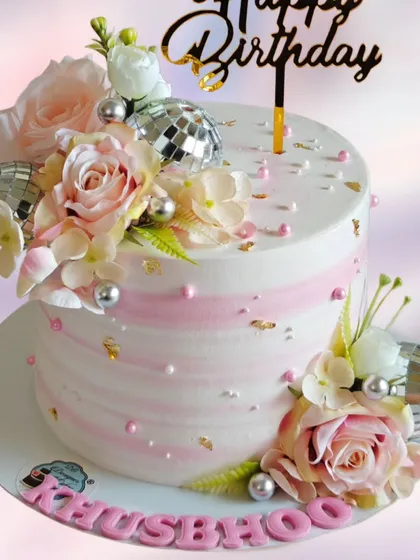 A birthday cake decorated with disco balls and fresh flowers. This design combines glamour and elegance for a fun and sophisticated party.