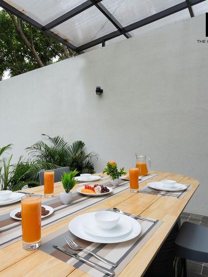 An outdoor dining table set up under a covered patio, perfect for guests to enjoy meals while being protected from the elements.