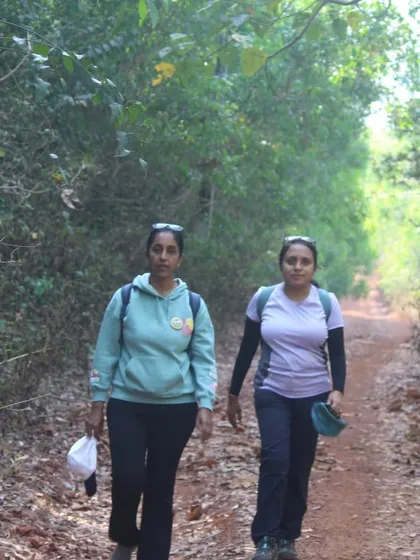 Two trekkers walking on a trail through the forest, part of the path connecting two beaches.