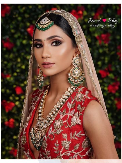 A portrait of bridal elegance. This bride wears a magnificent Kundan and pearl set with emerald drops, paired with a matching maang tikka and oversized statement earrings.