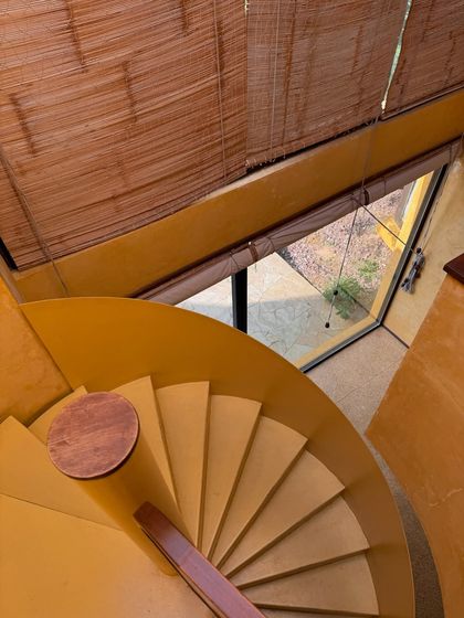 Looking down the spiral staircase, you see the bamboo blinds filtering the light, creating beautiful patterns on the floor below.