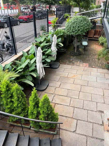 An overhead view of the courtyard at Sweet Smith in Bannimantap. The combination of stone paving, lush planters, and a manicured topiary tree creates a charming and well-maintained outdoor space for customers to enjoy.