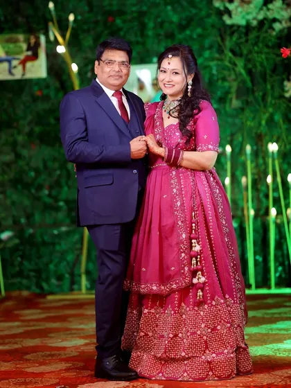A classic portrait of the anniversary couple against a lush green backdrop with decorative lights, perfect for a milestone celebration.