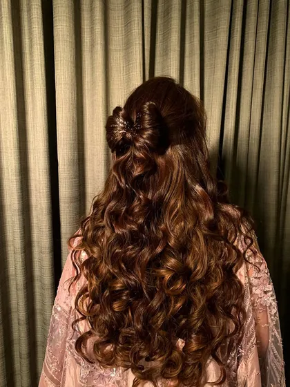 Loving this hair vibe. A cute hair bow made from her own hair, combined with long, natural curls, creates a playful and romantic look perfect for a pre-wedding event.
