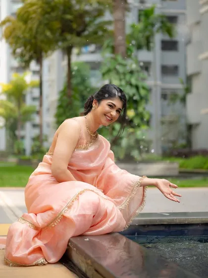 A candid shot of actress Aditi Prabhudeva enjoying a moment by the water. The playful splash of water adds a dynamic and joyful element to the portrait.