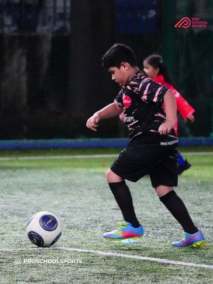 A young player dribbles with focus during a training session.
