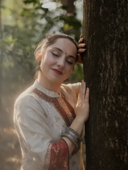An intimate and serene portrait of the dancer. Leaning against a tree with her eyes closed, this shot captures a quiet moment of connection between the artist and nature.
