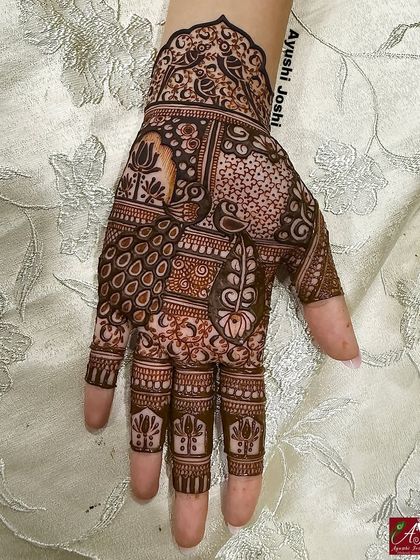 A detailed mehendi design for the groom's sister, featuring a mix of peacock, swan, and lotus motifs in a patchwork style.