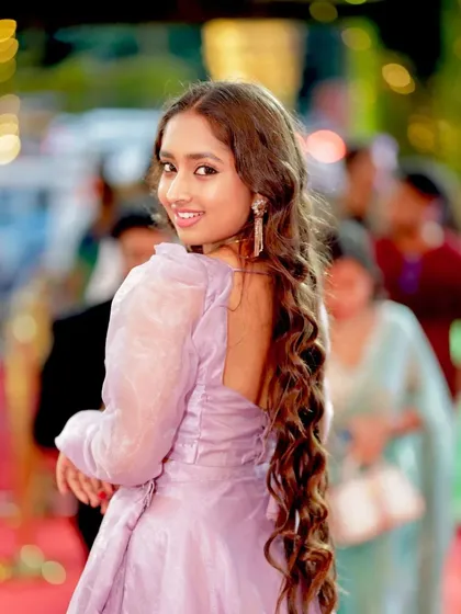 A lovely shot of Ankitha Jayarama looking back with a smile, her long hair adding to the elegance.