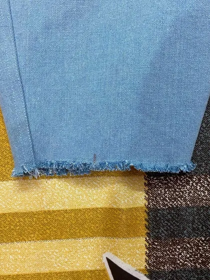 The frayed hem detail on a pair of custom cropped jeans. This is just one of the many finishing options available for your personalized denim.