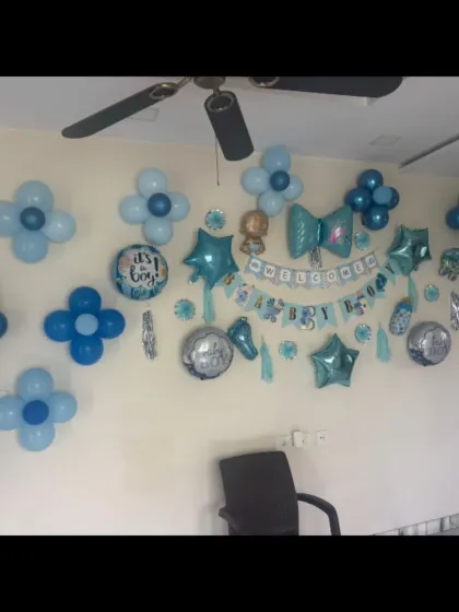 A wall decorated for a 'Welcome Boy' party, with blue and white balloon flowers and a themed banner.