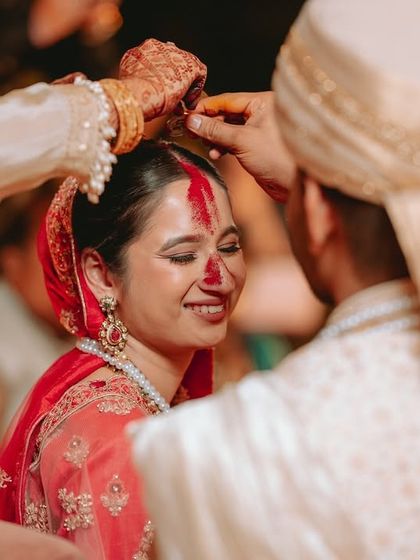 A close-up of the sindoor ceremony, capturing the bride's blissful smile as the ritual is performed.