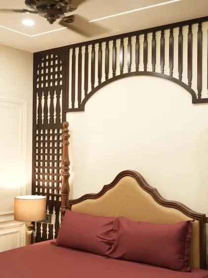 Showcasing our craftsmanship in traditional design, this bedroom features an ornate, dark wood jali headboard that creates a stunning focal point. This piece blends classic Indian heritage with contemporary comfort, demonstrating our design versatility.