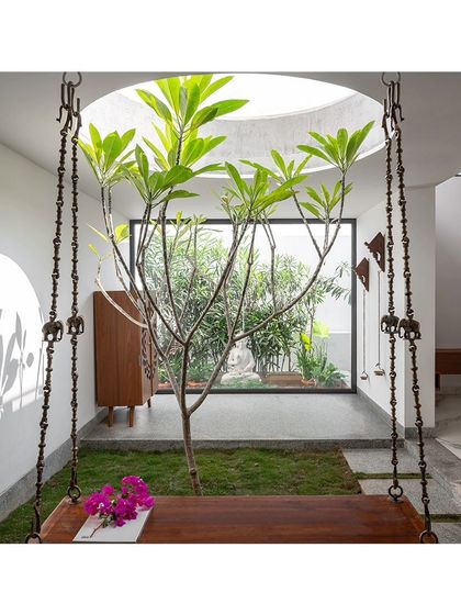 A view from the traditional wooden swing looking out into another green space. This composition of layered courtyards and framed views is a signature element, creating a sense of depth and continuous connection with nature.