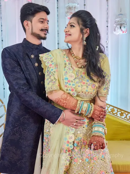 A beautifully composed portrait of a couple looking at each other. The intricate embroidery on their outfits and the bride's detailed henna are highlighted.