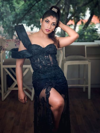 A full-length shot of actress Iti Acharya in an elegant black gown. This photo highlights the dress's unique design and is suitable for fashion features or red carpet-style portfolios.