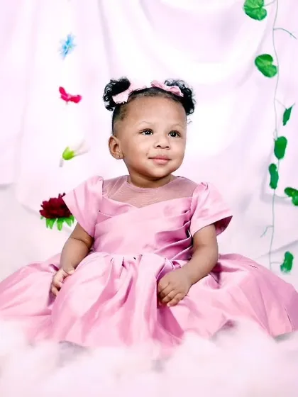 A princess in a pink gown, sitting among clouds and hanging flowers.