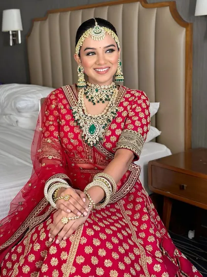 A happy bride seated and ready for her big day. The complete look, from the makeup to the jewelry placement, is meticulously planned and executed.
