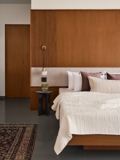 A bedroom view highlighting the contrast between the warm, vertical wood panelling and the soft, horizontal lines of the bed and textiles.