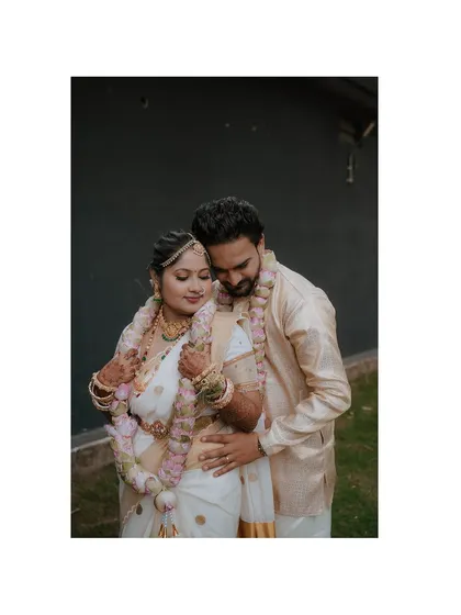 A tender moment from a Kerala-style wedding. The couple, adorned in traditional garlands, shares a quiet embrace, capturing the deep emotion and sanctity of the occasion.