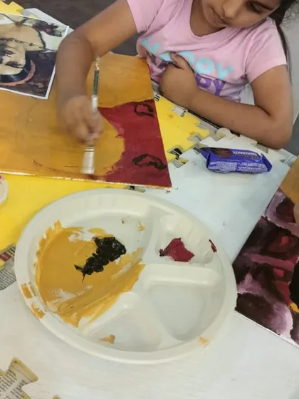 Mixing the perfect skin tone is a key skill in portrait painting. Here, a student experiments with colors on her palette before applying them to her Amrita Sher-Gil-inspired artwork.