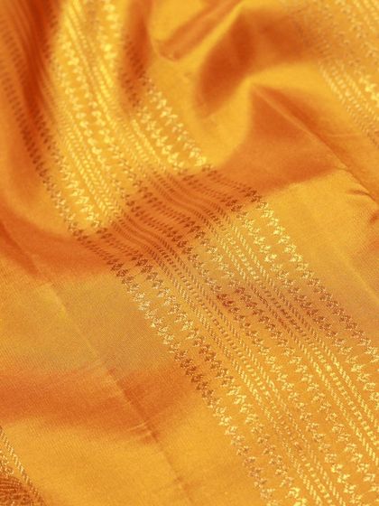 A close-up of the rich texture of a yellow silk saree, showcasing the fine weaving.