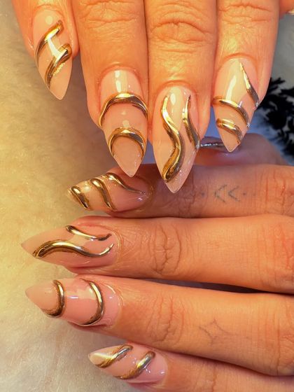 This design features bold, 3D gold chrome waves sculpted over a neutral, almond-shaped nail extension. The result is a futuristic, liquid-metal effect that is both edgy and incredibly glamorous.