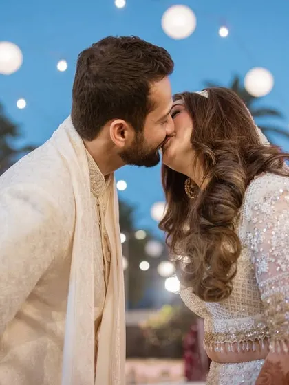 A perfect kiss against a backdrop of twinkling lights. We specialize in creating romantic couple portraits that feel both magical and authentic, like this beachside Nikaah moment.
