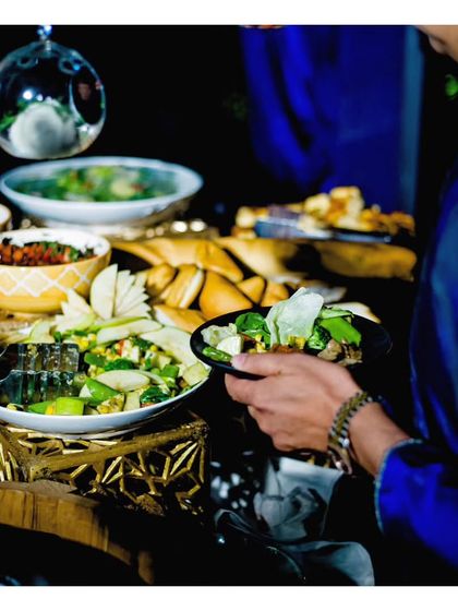 A guest helps themselves to a dish from a buffet line. Our buffet setups are designed for easy and elegant self service, ensuring a smooth flow for guests.