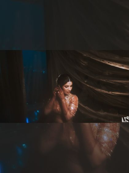 A moody, atmospheric portrait of Vedika getting ready. The dark tones and soft focus create a dreamy, intimate feel, capturing a private moment of preparation.